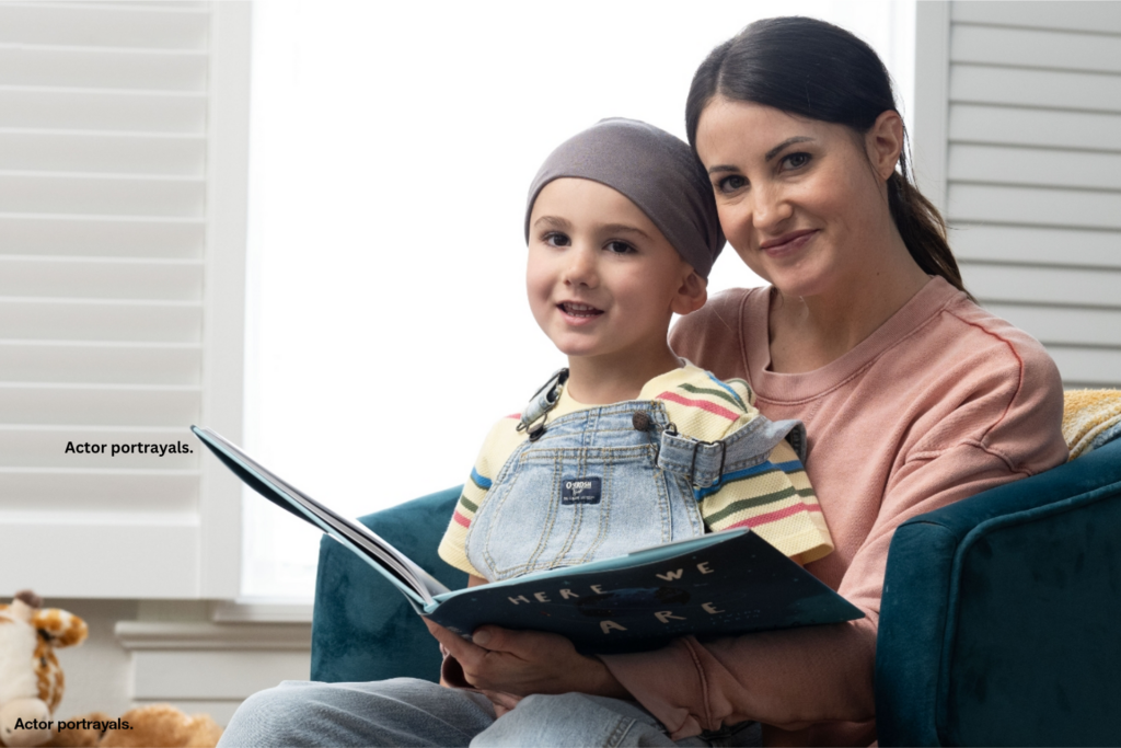 Woman and her son who has a head wrap sitting in bedroom reading a book.
